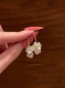 Close-up of elegant gold hook earrings featuring white pearl flowers and crystal balls
