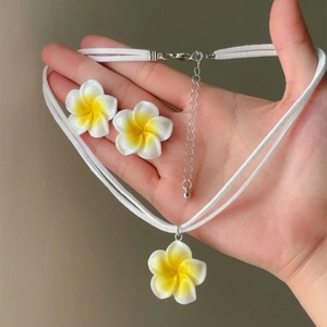 Hand-held view of Hawaii style yellow and white frangipani flower necklace and earrings set