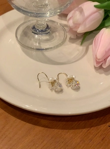 Close-up of elegant gold hook earrings featuring pearl flowers and sparkling crystal balls
