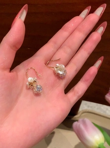 Detailed macro shot of elegant gold flower earrings with sparkling crystal balls in hand