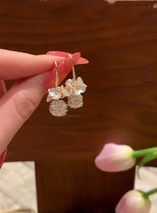Detailed shot of elegant gold hook earrings featuring pearl flowers and crystal balls