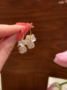 Close-up detail of delicate white flower ear hook earrings with clear faceted crystal globes