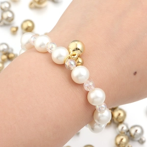 Vue détaillée d'un bracelet de perles élégant avec breloque cloche dorée au poignet