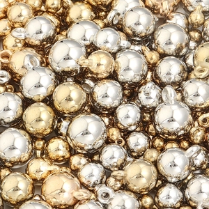 Gros plan de perles métalliques rondes dorées et argentées avec anneaux pour bijoux DIY