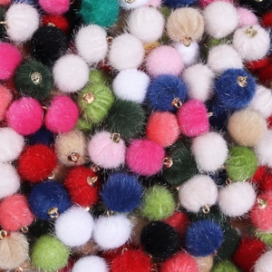 Detail van kleurrijke imitatiebont pompons met gouden hangers voor DIY-sieraden