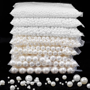Vertical stack of multi-sized white ABS pearls in individual clear bags on black backdrop
