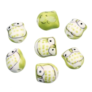 Gros plan de sept perles de hibou en céramique peintes à la main pour bijoux DIY vert et blanc