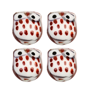 Vue macro détaillée de quatre perles chouettes en céramique peintes pour bijoux DIY