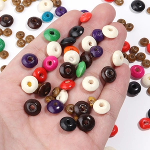 Colorful mix of flat round wooden beads for DIY jewelry making held in palm