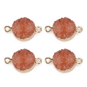 Nahaufnahme von Pfirsich-Druzy-Anhängern mit Goldrand und doppelten Ösen für DIY