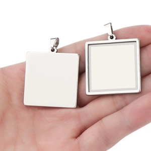 Detailed view of square stainless steel blank pendant trays held in palm for DIY jewelry