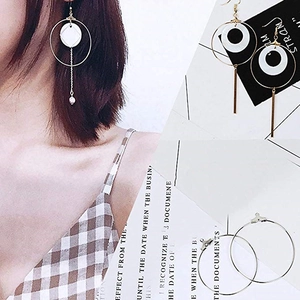 Detail of gold-plated geometric drop earrings with large round hoops and white shell discs