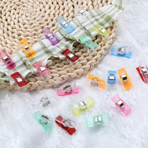 Colorful plastic sewing clips for quilting and fabric binding on a craft background