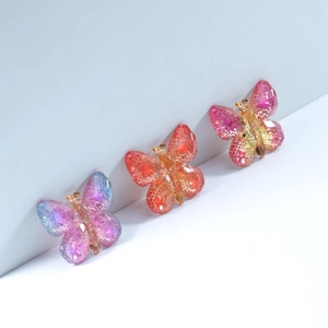 Macro view of gradient acrylic butterfly charms with glitter and realistic wing textures