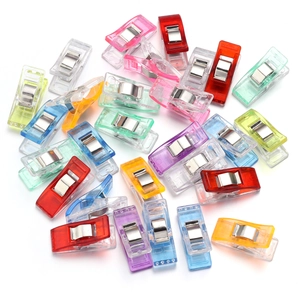 Colorful sewing clips for fabric quilting and patchwork crafts on white background