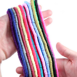 Bunte Heishi-Perlen aus Polymer-Ton für DIY-Schmuck in den Händen präsentiert