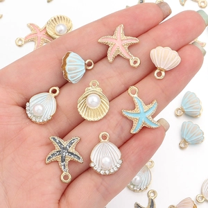 Pendentifs océaniques en alliage avec coquillages et étoiles de mer présentés dans la main