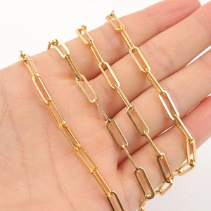 Macro shot of gold plated stainless steel paperclip chain held in hand for scale