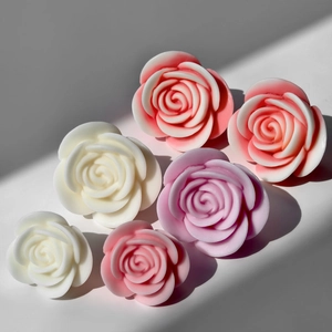 Handmade rose flower candles in pink and purple colors on white background