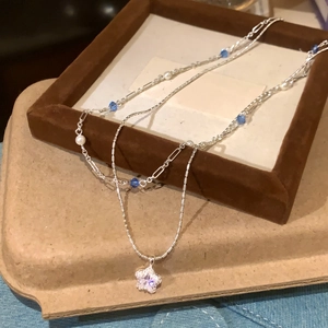 Close-up of elegant double-layer necklace with star zircon pendant and blue bead accents