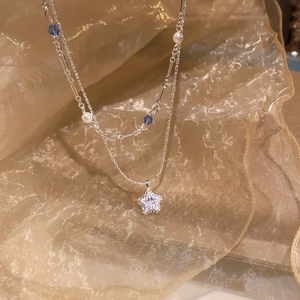 Detail of silver double-layer necklace with a sparkling star pendant and blue crystal beads.