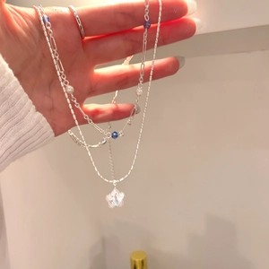 Close-up of silver double-layered necklace with zircon star pendant and blue beads