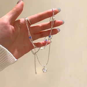 Detailed view of a silver double-layer necklace featuring a sparkling star pendant.