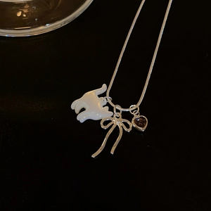 Détail rapproché d'un collier en argent avec pendentifs chat en nacre, nœud et cœur
