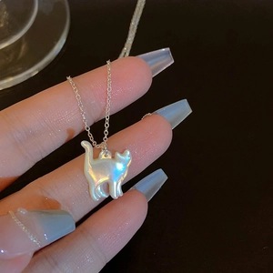 Gros plan d'un collier pendentif chat en nacre irisée avec une chaîne en argent délicate.