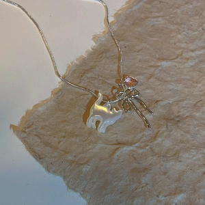 Gros plan sur un collier pendentif chat en nacre avec nœud argenté et gemme rose