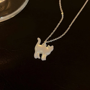 Gros plan d'un collier pendentif chat en nacre élégant sur une surface sombre et texturée