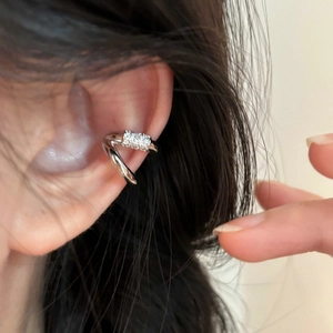 Λεπτομερές κοντινό πλάνο ενός ασημένιου ear cuff διπλής στρώσης με ζιργκόν στο αυτί ενός μοντέλου