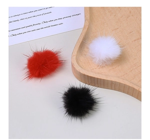 Macro shot of colorful fluffy faux fur pom-poms in red, white and black for DIY crafts