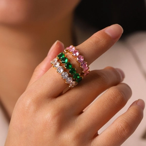 Detailed view of stacked 18k gold rings with pink, green, and white zircon stones