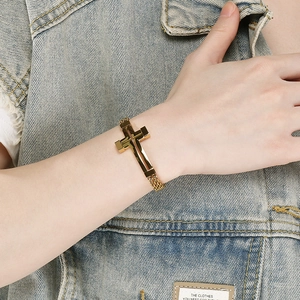 Detailaufnahme eines Retro-Armbands aus Edelstahl mit Kreuz und goldenem Netzgewebe