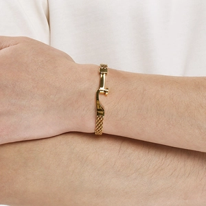 Detailaufnahme eines vergoldeten Herrenarmbands mit gebogener Stange und Mesh-Kette.