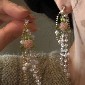 Close-up of vintage French rose earrings with delicate pearl tassels and floral details.