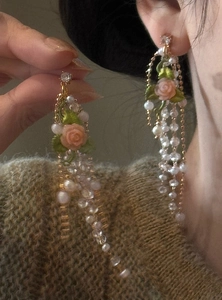 Detailed macro shot of elegant French vintage rose and pearl tassel earrings on model