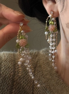 Detailed macro view of French retro earrings featuring pink rose, pearls and long tassels