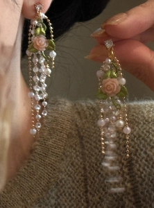 Macro view of French retro long tassel earrings featuring pink roses and pearls.