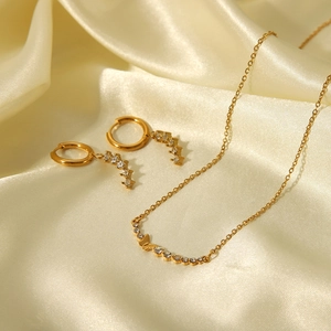 Detailed close-up view of elegant gold butterfly necklace and earring jewelry set on silk