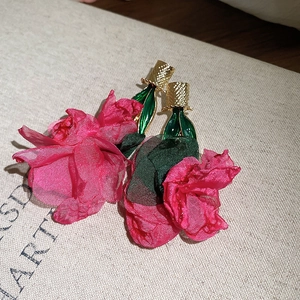 Detailed view of handmade pink chiffon rose earrings with green enamel leaf accents.