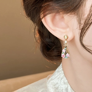 Close-up view of pink peach blossom pipa earrings worn on the ear with a gold finish.