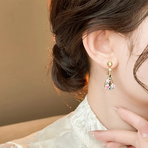 Close-up of elegant Pipa-shaped earrings with pink peach blossom details