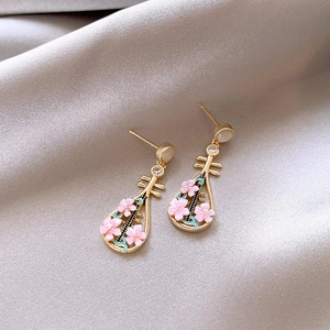 Close-up detail of gold-tone Pipa lute drop earrings featuring pink peach blossom