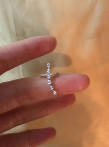 Detailansicht eines silbernen Kreuz-Ohrklemmen mit funkelnden Zirkoniasteinen in Tropfenform.