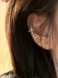 Detaillierte Ansicht eines eleganten silbernen Kreuz-Ohrclips mit Kristallen am Ohr