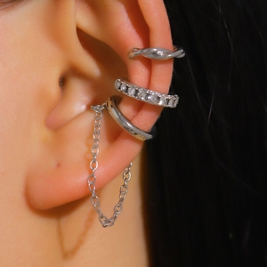 Detailed close-up of three-piece silver ear cuff set with rhinestones and chain detail