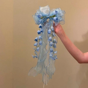 Close-up detail of a light blue Lily of the Valley bow hair clip with long lace tassels