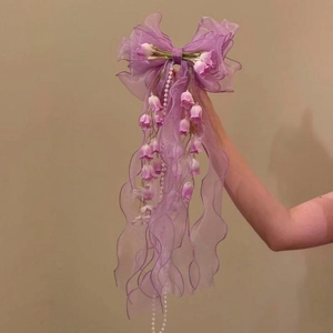 Detailed view of large purple lace bow hair clip with lily of the valley and pearls